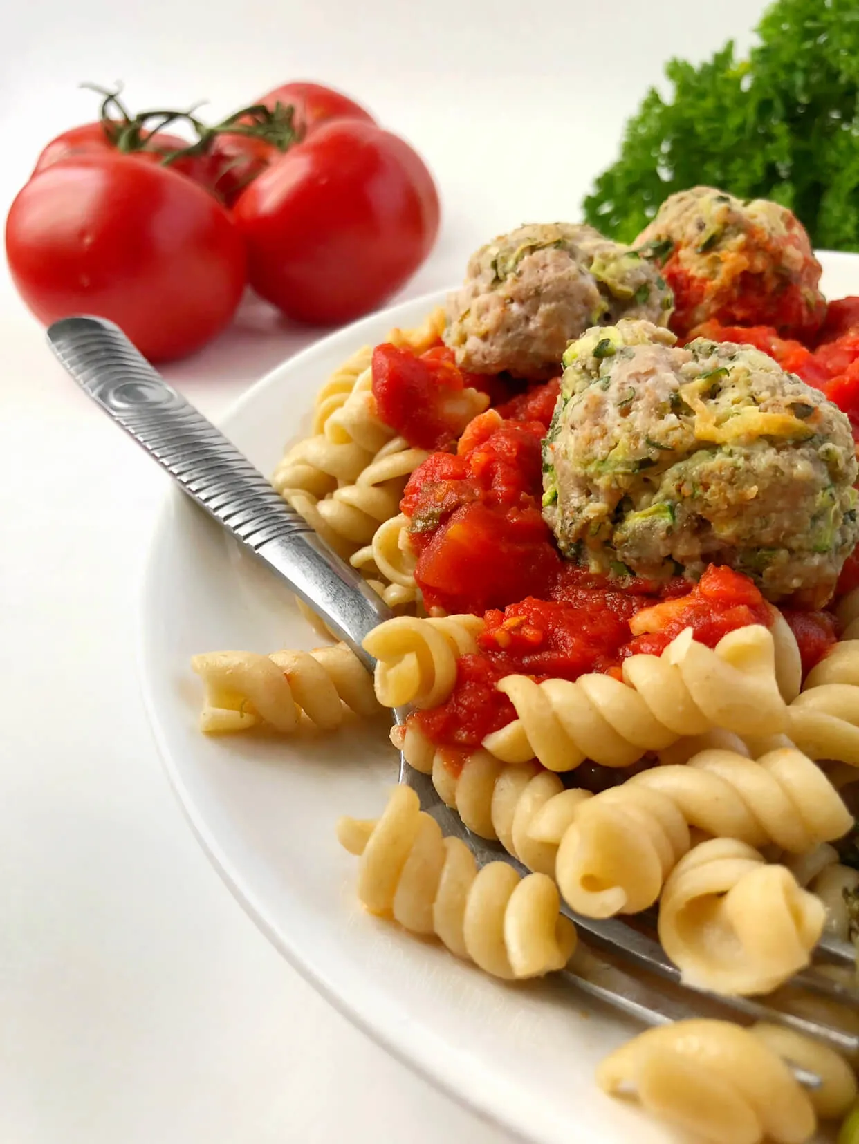 pork zucchini meatballs on a bed of pasta with sauce