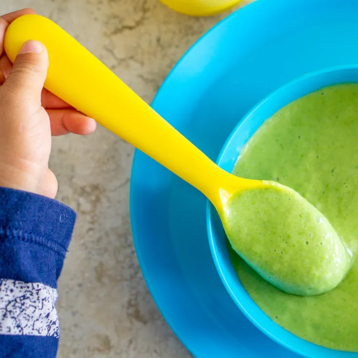 toddler holding baby food spoon