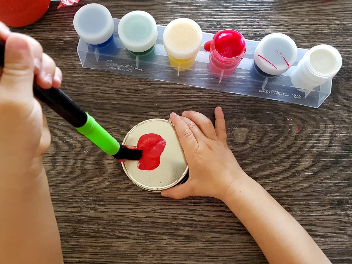 toddler painting a jar lid