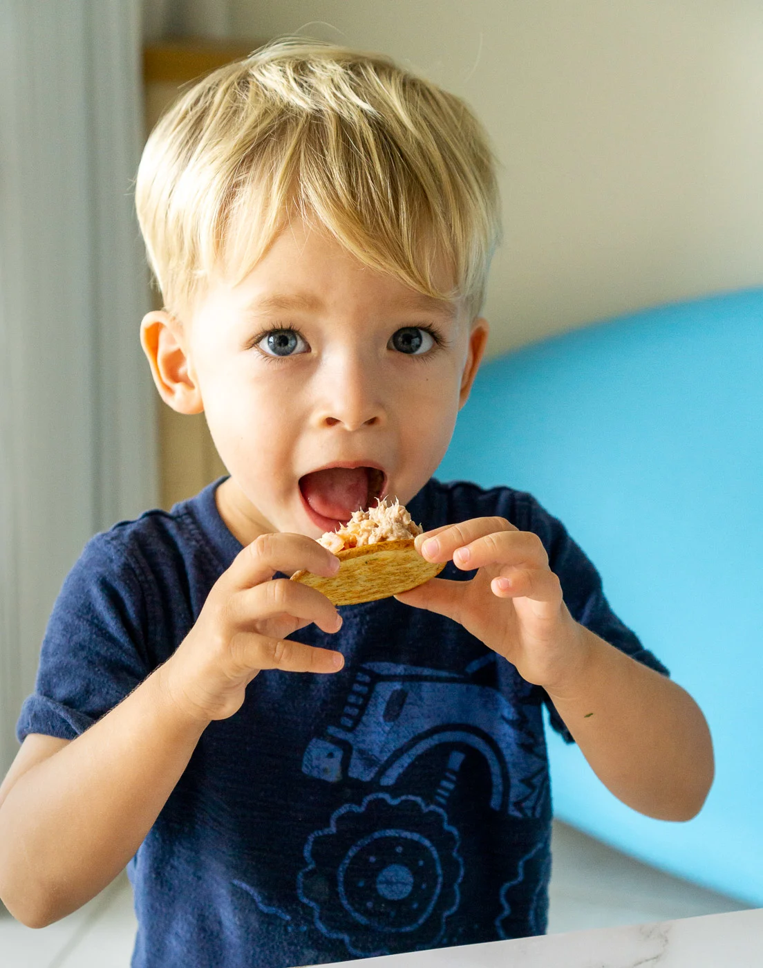 toddler eating cracker with tuna salad