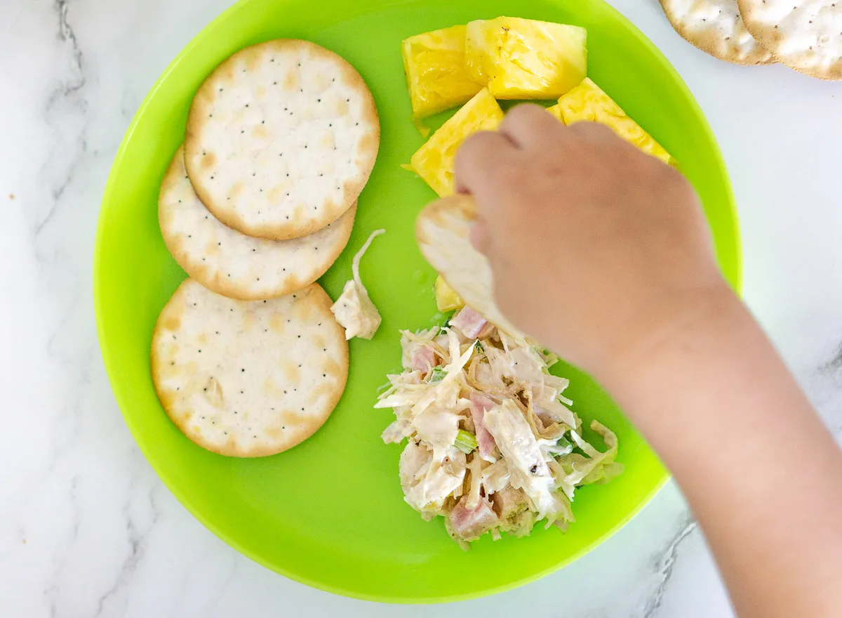toddler eating Hawaiian chicken salad with pineapple