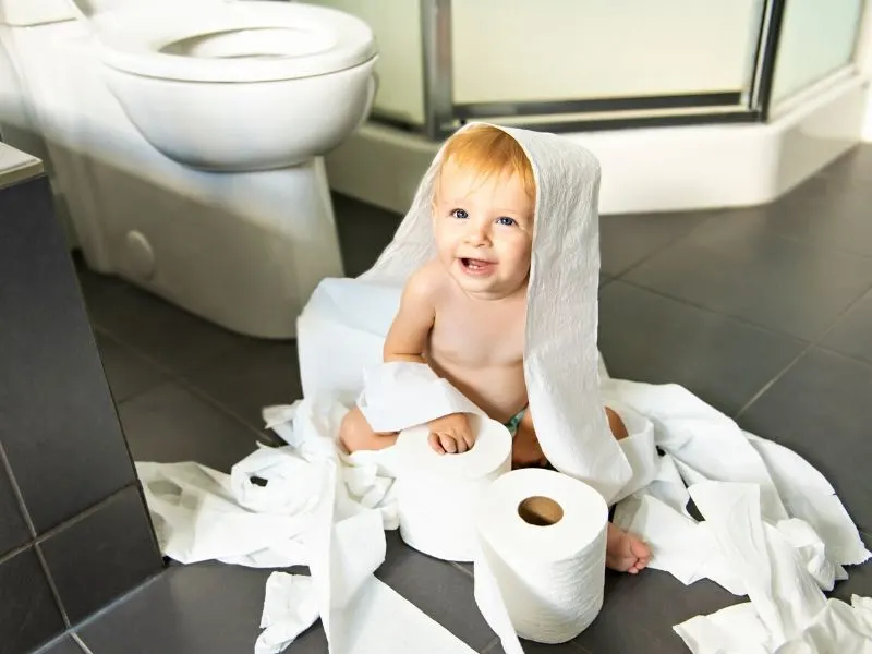 toddler playing with toilet paper