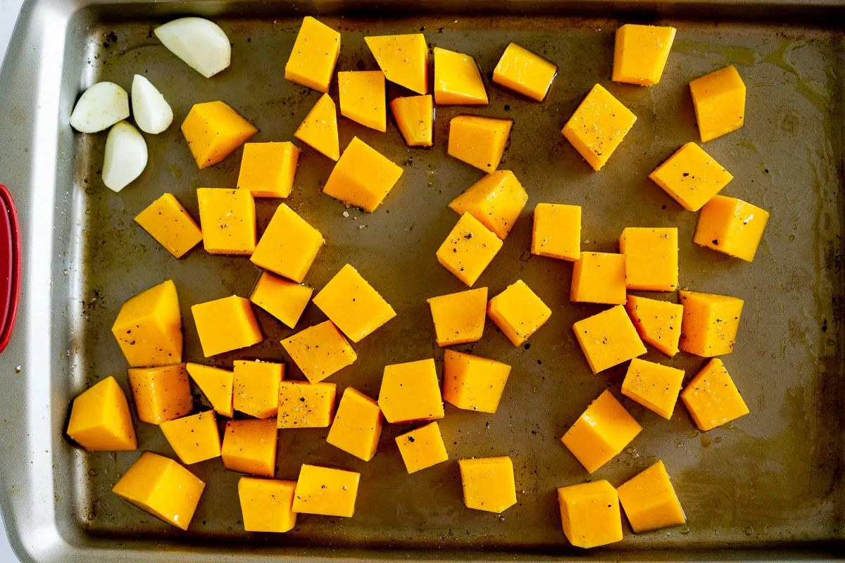 cubed butternut squash and garlic on a baking sheet