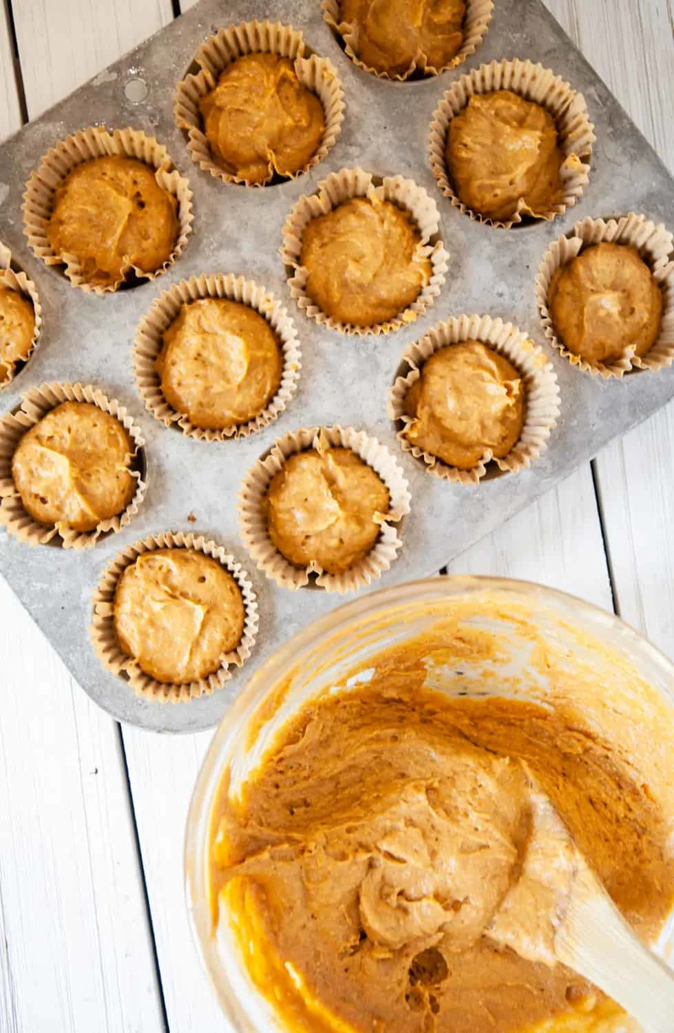 pumpkin muffin batter being spooned into a muffin tin