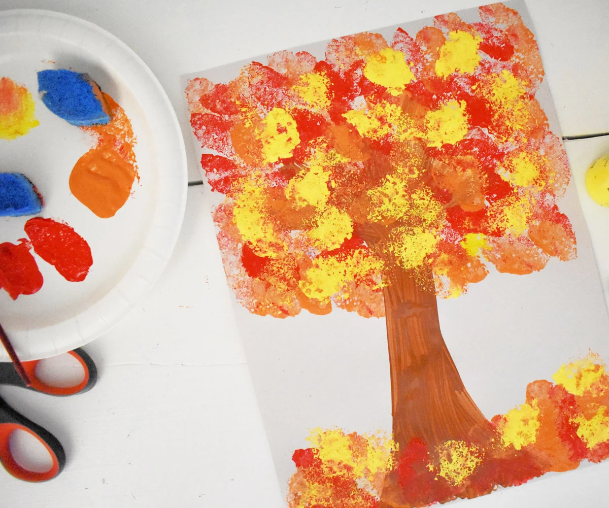sponge stamped tree next to paper plate with finger paints and scissors - a Fall craft for toddlers