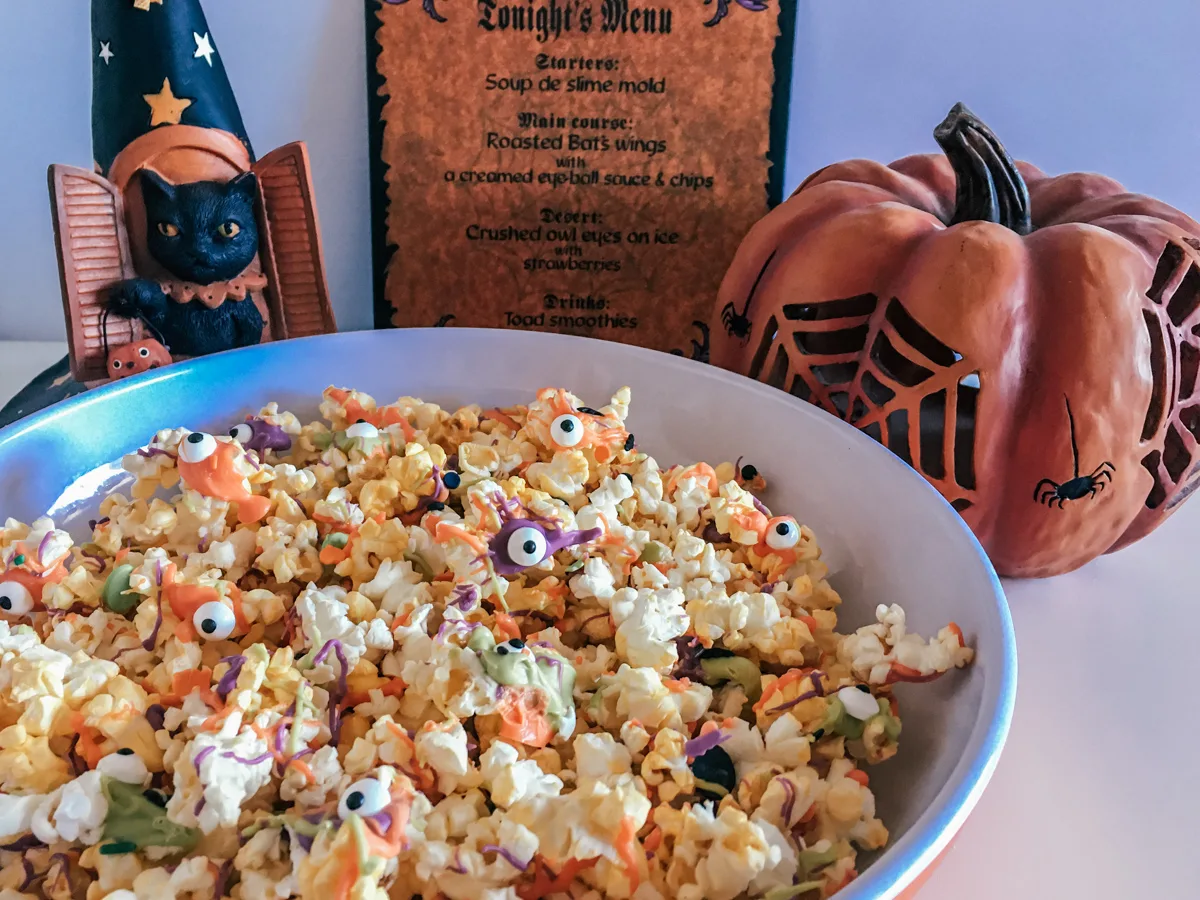 bowl of Monster Popcorn for a Halloween party next to Halloween decorations