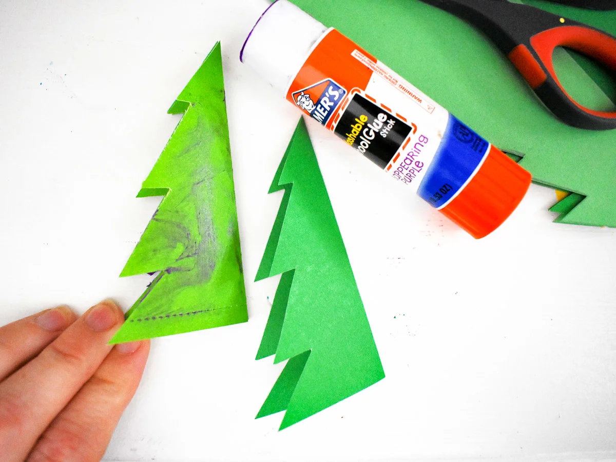 2 paper christmas trees and a glue stick to make a christmas tree craft