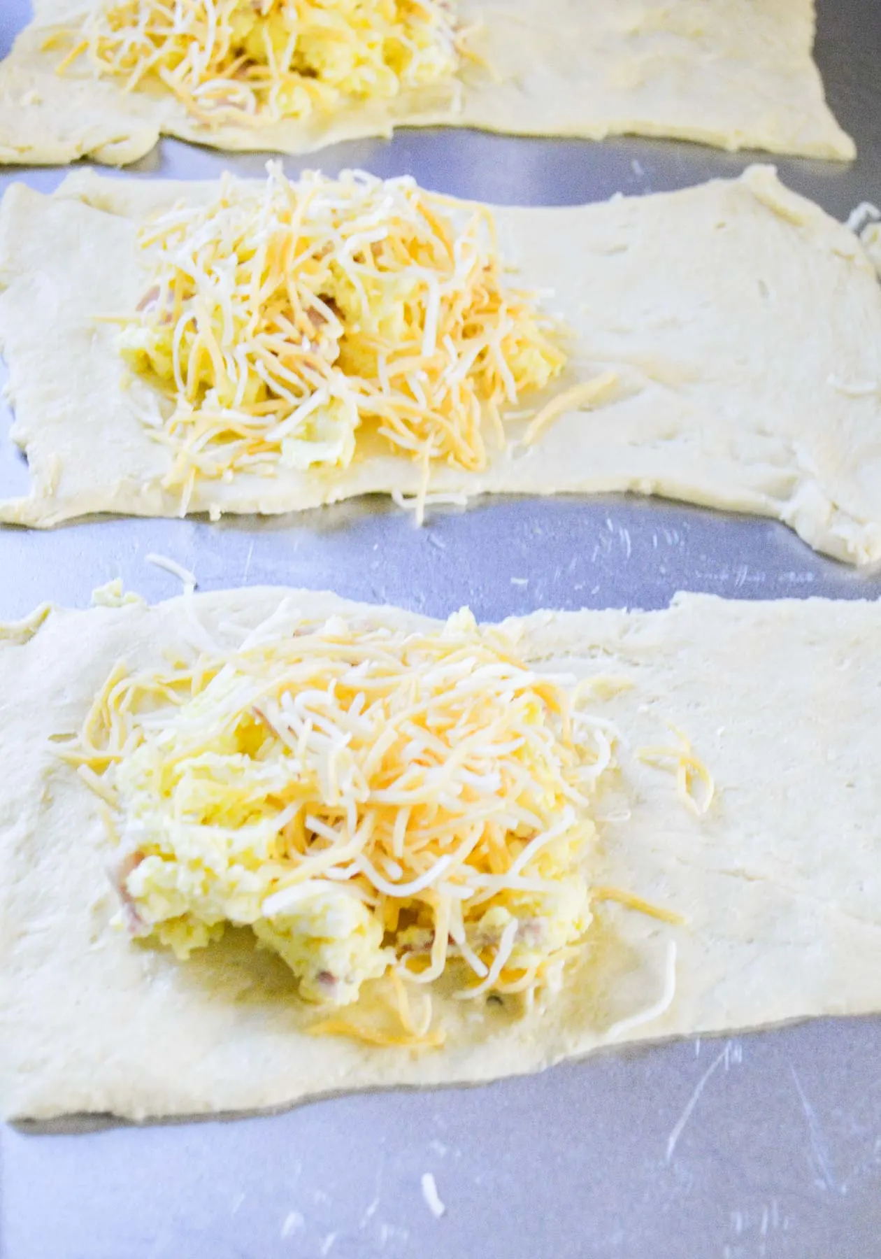 adding cheese to crescent dough breakfast pockets