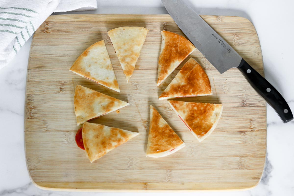 Pizza quesadillas cut into wedges on a cutting board.