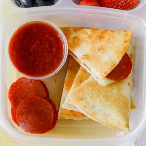Pepperoni pizzadillas with pizza sauce in a lunch container.