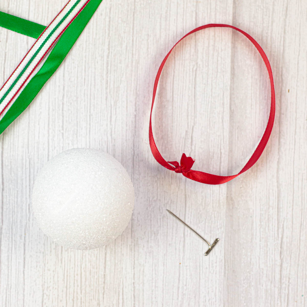 Christmas ribbon tied in a loop next to a Styrofoam ball.