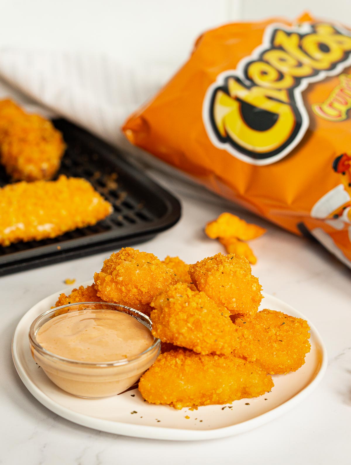 Cheetos chicken nuggets on a plate with dip.