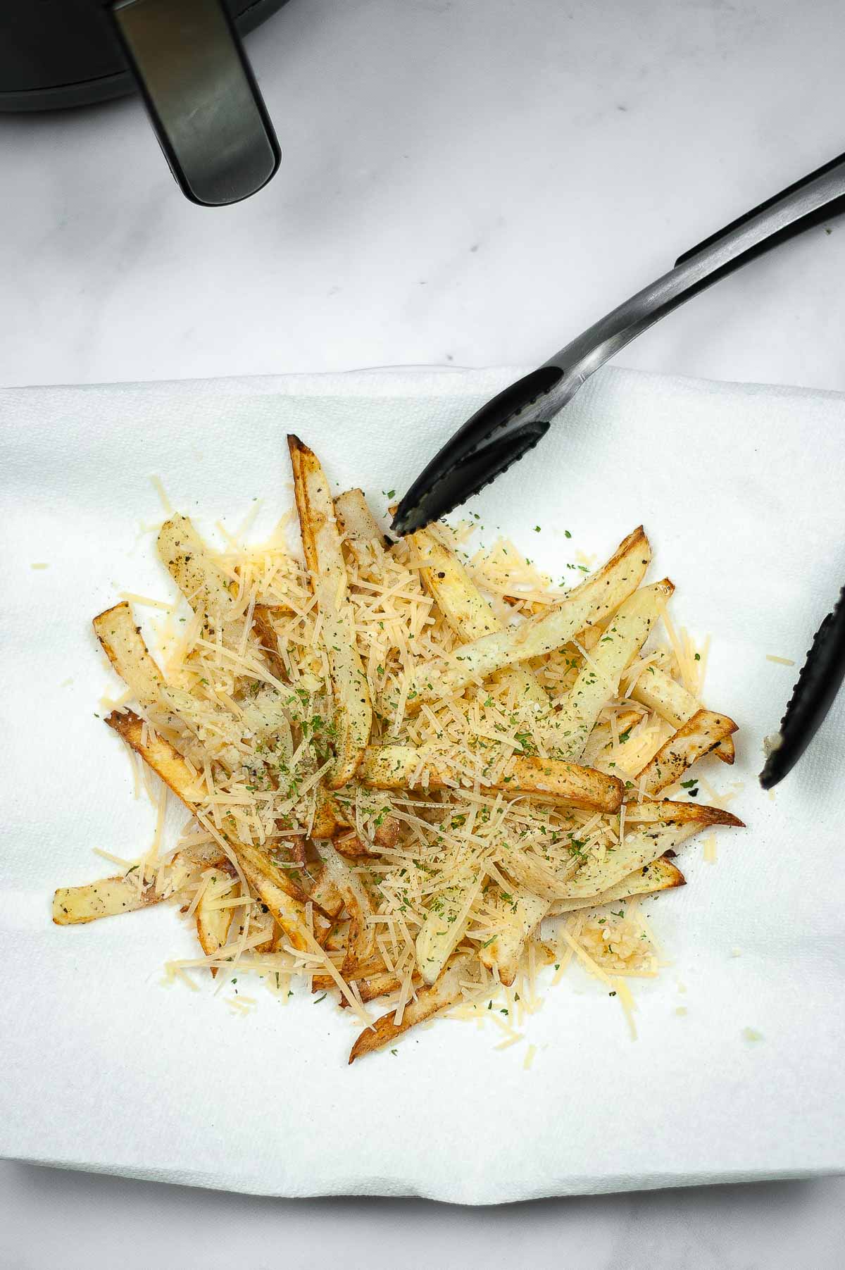Tossing air fryer French fries with garlic and shredded parmesan