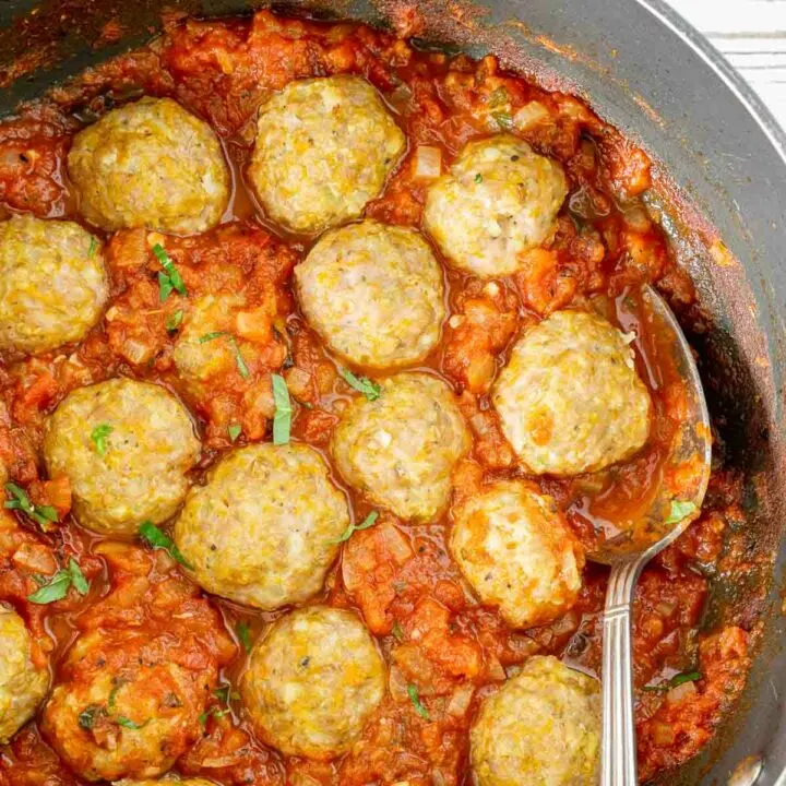 Ground pork meatballs in a pan with tomato sauce